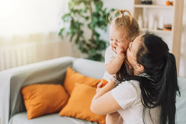 Young Mother Hugging Kissing Her Baby While Sitting Couch — 스톡 사진