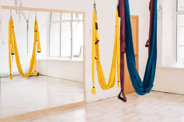 Hanging hammocks in front of a mirror in the fly yoga room.