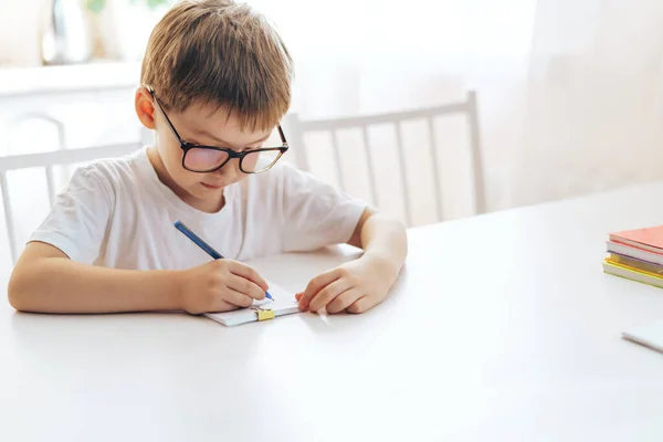 Хлопчик Окулярах Пише Листи Блокноті Ручкою — стокове фото