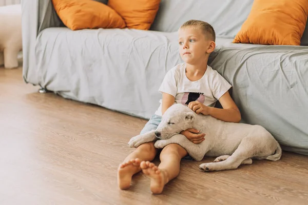 The puppy sleeps with its head resting on the boys feet.