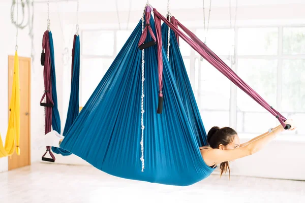 Girl doing fly yoga lying in a hammock.