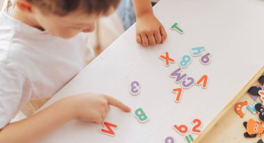 Primary school student studying letters while sitting at the table.