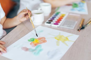 The child painted flowers and the sun with paints.