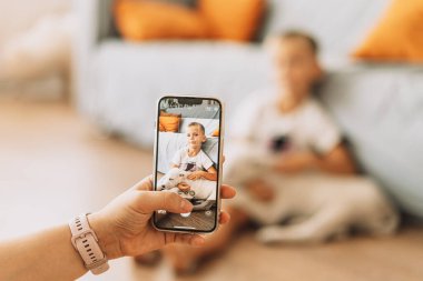 The girl takes a picture on the phone of a child with a puppy.