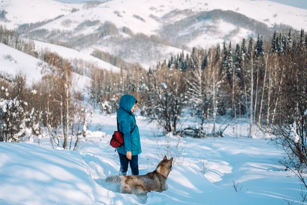 Girl with a dog walking in the snow in the forest.