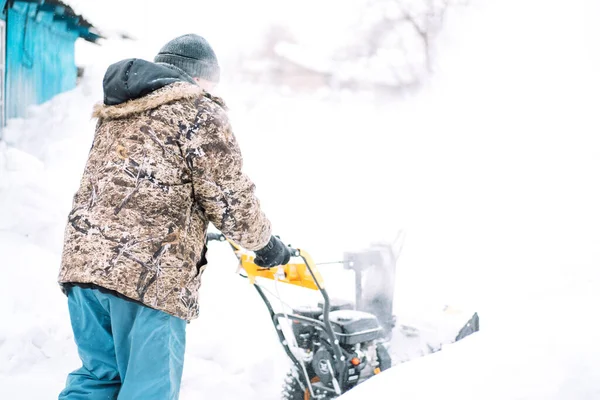 Man clearing snow with a snow blower.