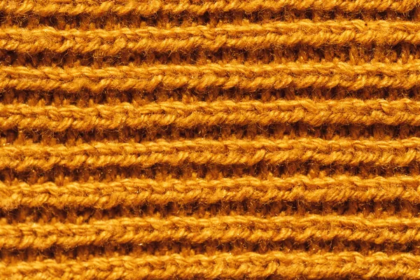 Background of yellow knitted woolen thread close-up.