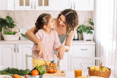 Anne ve kızı salatayı ahşap spatulalarla karıştırıyorlar..