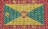 Detailní záběr na cihlovou zeď s Grenadovou vlajkou..