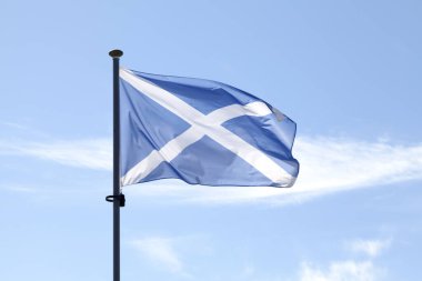 İskoç Saltire bayrağı (St. Andrew 's Cross) mavi gökyüzüne karşı direğinin tepesinde dalgalanıyor