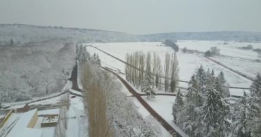 Top-down tracking shot of an equestrian training ground covered by snow during the winter.