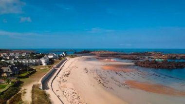 The beach of the Greve Blanche (White strike) in Tregastel with small boats navigating between granite rocks and the Ile aux Lapins (Island of rabbits).