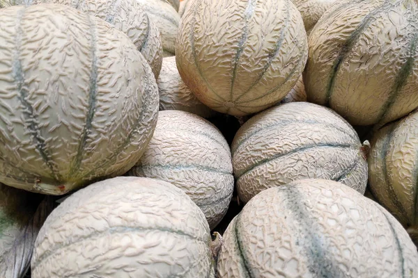 Full frame close-up on a stack of cantaloupes on a market stall.