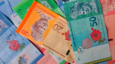 Arka plan olarak dönen Malezya ringgit banknotları yığını.