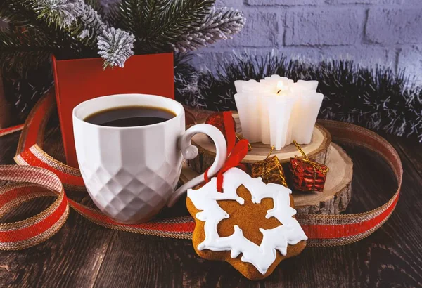 Gingerbread, a cup of coffee and a candle. Festive Christmas and New Year composition with a gift ribbon. Wooden background and branches of the Christmas tree. Side view.
