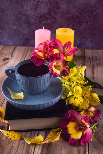 アロステミアの黄色と紫色の花 コーヒーの青いカップ ろうそくと本とロマンチックな組成物 トップ表示 — ストック写真