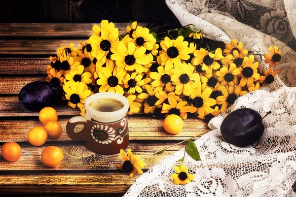 Rudbeckia flowers and a cup of coffee with autumn fruits on the window. Plums and yellow plums on the windowsill. Side view.
