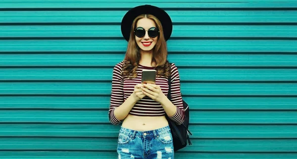 Portrét Šťastné Usmívající Mladé Ženy Chytrým Telefonem Klobouku Modrém Pozadí — Stock fotografie