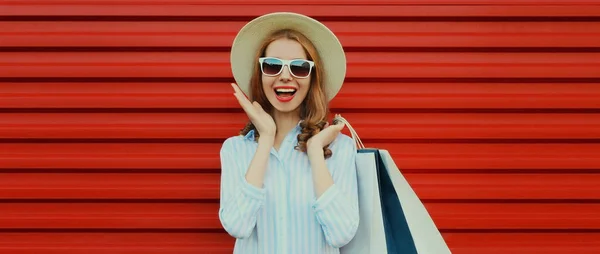 幸せの肖像画幸せな笑いの女性でショッピングバッグを身に着けているわらラウンド帽子とシャツカラフルな赤の背景 — ストック写真