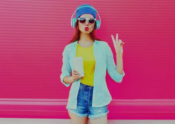 ピンクの背景にヘッドフォンで音楽を聴く現代の若い女性のカラフルな夏の肖像画 — ストック写真
