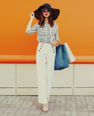 Beyaz çizgili gömlek giyen, turuncu arka planda siyah şapkalı güzel bir genç kadının portresi.