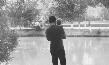 Genç babanın silueti ve nehir kenarında küçük bir çocuk.