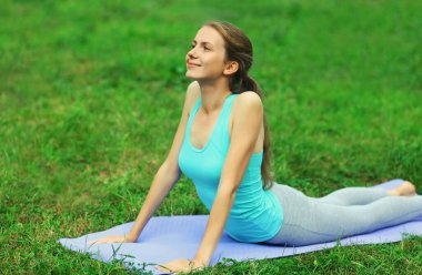 Spor salonundaki kadın yoga egzersizleri yapıyor yaz parkında çimlerin üzerinde esniyor.