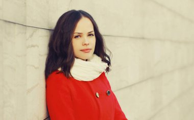 Güzel, esmer bir kadının portresi. Kırmızı ceketli, açık havada eşarp takıyor.