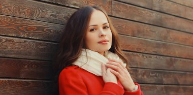 Güzel, esmer bir kadının portresi. Kırmızı ceketli, açık havada eşarp takıyor.