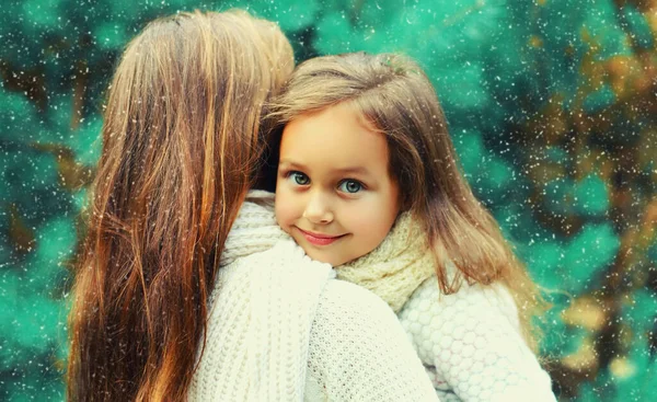 Kış portresi mutlu gülümseyen anne ve küçük kız çocuğunun Noel ağacı arka planında