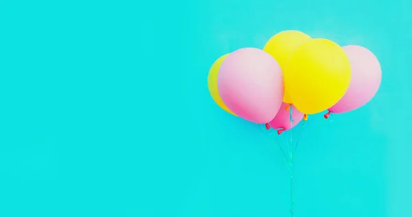 青い背景にお祝いのカラフルな黄色のピンクの風船の束 — ストック写真