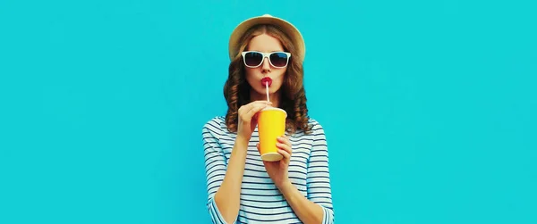 穿着夏草帽和蓝色背景条纹T恤 喝新鲜果汁的年轻女子的画像 — 图库照片