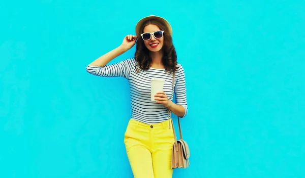 穿着手提包 条纹T恤和蓝色背景夏草圆帽 头戴咖啡杯 笑容满面的年轻女子的画像 — 图库照片
