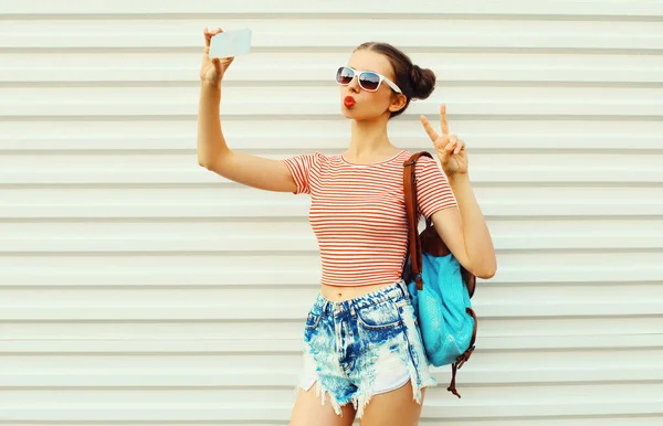 Portrait Happy Young Woman Taking Selfie Smartphone Wearing Backpack White — стоковое фото