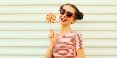 Beyaz arka planda lolipopu olan mutlu gülümseyen genç bir kadının yaz portresi