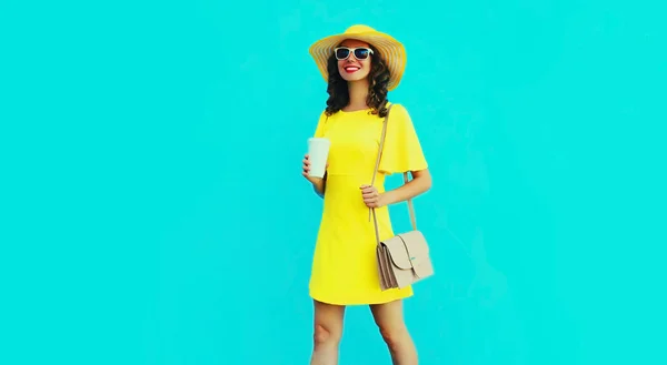 美丽的笑容可亲的女人的画像 一杯咖啡 戴着黄色夏帽 穿着蓝色背景的衣服 — 图库照片