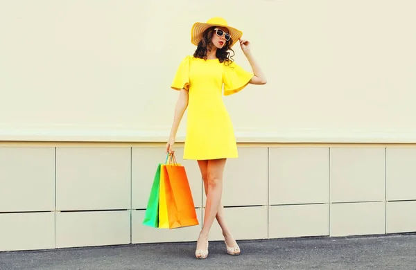 街で黄色のドレスと夏のわらの帽子を身に着けているショッピングバッグと美しい幸せな笑顔の女性 — ストック写真