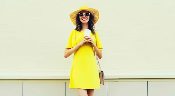 黄色のドレスを着てコーヒーのカップと美しい笑顔の若い女性の肖像画 白い背景に夏の帽子 — ストック写真