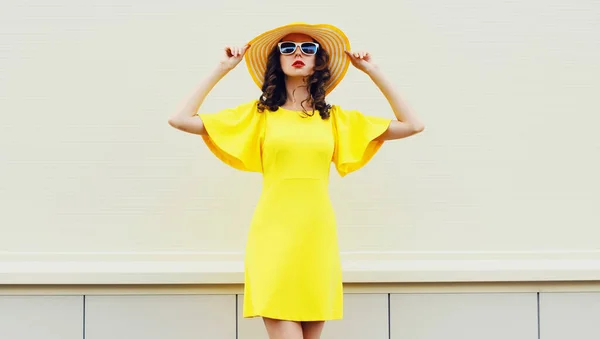 黄色のドレスを着て美しい若い女性の肖像画 街の通りの背景に夏のわら帽子 — ストック写真
