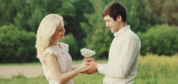 在绿色的夏天背景下 一对快乐可爱的年轻夫妇抱着一束野花紧紧相拥在一起 — 图库照片