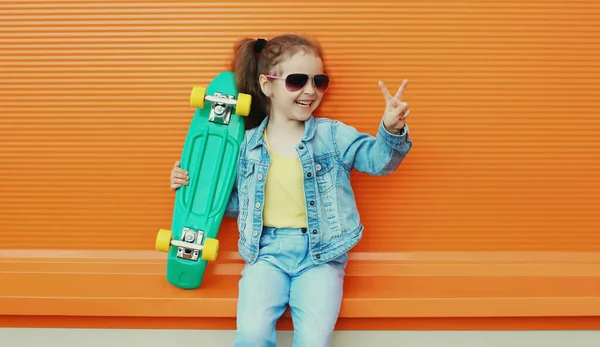 Portret Râs Veselă Fetiță Copil Pozând Skateboard Oraș Fundal Portocaliu — Fotografie, imagine de stoc