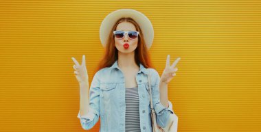 Kırmızı dudak üfleyen kadının portresi turuncu arka planda tatlı bir öpücük yolluyor.