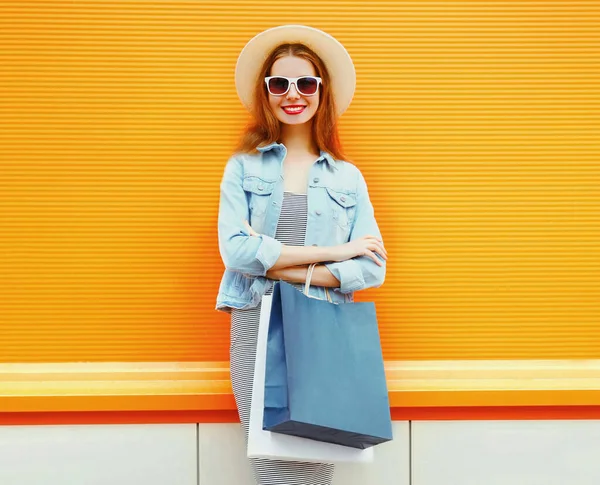 穿着夏草帽 头戴橙色背景的购物袋的快乐年轻女性的画像 — 图库照片
