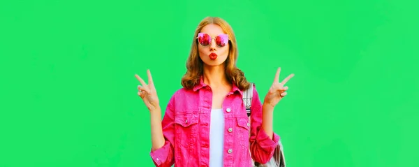 美丽的年轻女子挥动着红唇 穿着粉色夹克 戴着绿色背景太阳镜 在甜美的空气中亲吻着美丽的肖像 — 图库照片