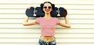 Beyaz arka planda kaykayla poz veren neşeli genç bir kadının yaz portresi.