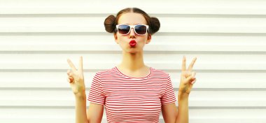 Dudaklarını silen genç bir kadının portresi kırmızı rujlu tatlı hava öpücüğü beyaz arka planda havalı saç stili olan çizgili tişört giyiyor.