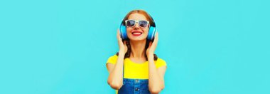 Renkli mavi arka planda kulaklıkla müzik dinleyen mutlu bir kadının portresi.