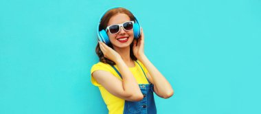 Renkli mavi arka planda kulaklıkla müzik dinleyen mutlu bir kadının portresi.