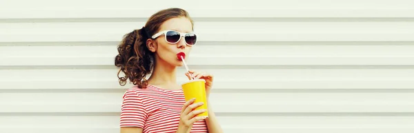 若い女性の肖像白を背景にクールな髪型で縞模様のTシャツを着て新鮮なジュースを飲む — ストック写真
