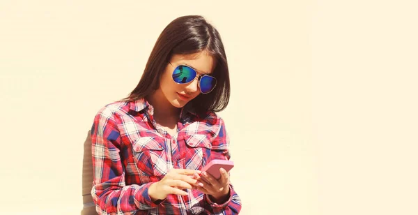 在阳光明媚 背景洁白的夏日里拿着智能手机的年轻女子的画像 — 图库照片